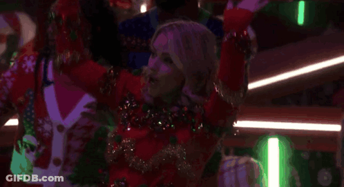 A Woman In A Red Sweater Is Dancing In A Club With Other People . GIF