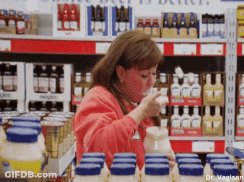 A Woman In A Red Sweater Is Drinking From A Pitcher In A Store GIF