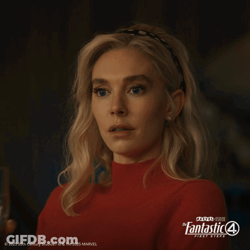 A Woman In A Red Sweater Is Holding A Glass Of Water In Front Of A Poster For The Fantastic 4 First Steps GIF