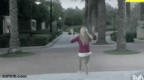 A Woman In A Red Sweater Is Running Down A Sidewalk . GIF