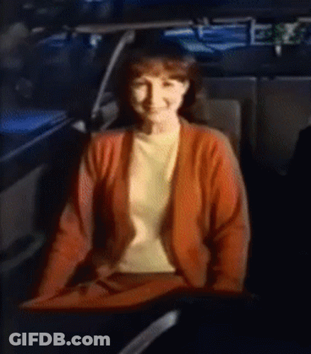 A Woman In A Red Sweater Is Sitting In The Back Seat Of A Car GIF