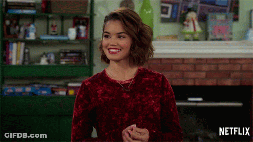 Woman In Red Sweater Smiling In Front Of Fireplace GIF