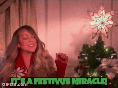 A Woman In A Red Sweater Is Standing In Front Of A Christmas Tree And A Star . GIF