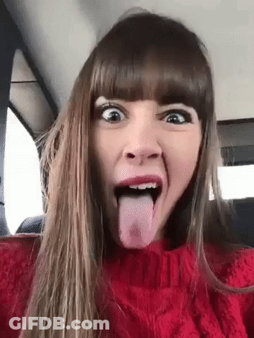 A Woman In A Red Sweater Is Sticking Her Tongue Out In A Car . GIF