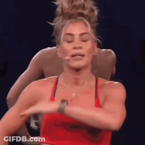 A Woman In A Red Tank Top Is Dancing With A Man In A Blue Shirt Behind Her . GIF