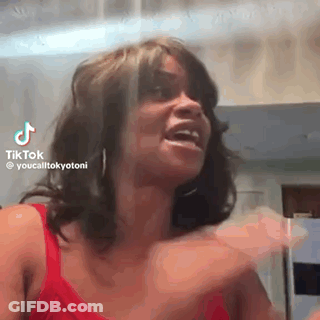 A Woman In A Red Tank Top Is Making A Funny Face And Laughing . GIF