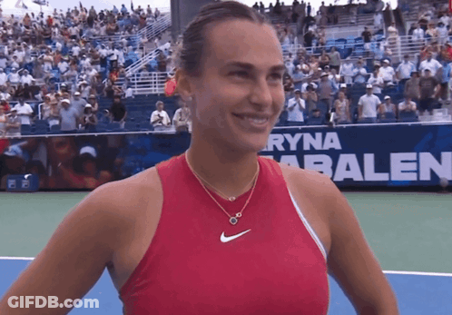 A Woman In A Red Tank Top Is Smiling On A Tennis Court GIF