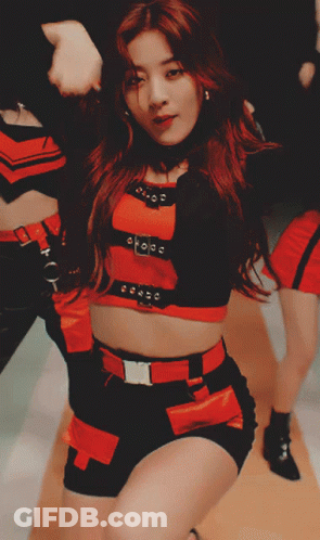 A Woman In A Red Top And Black Shorts Is Dancing With Her Hands In The Air GIF
