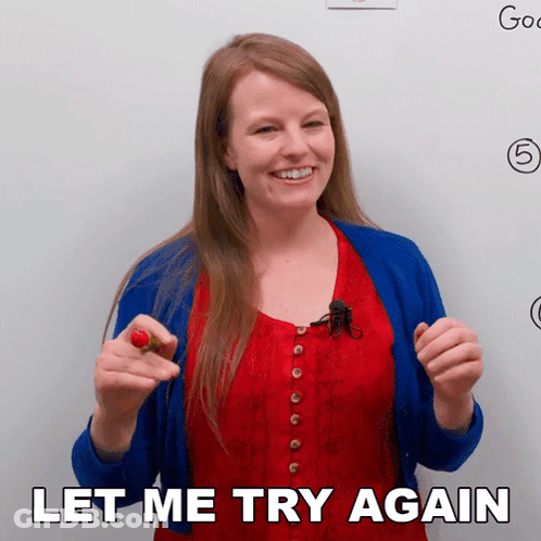 A Woman In A Red Top And Blue Cardigan Is Holding A Red Flower And Says Let Me Try Again GIF