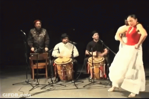 A Woman In A Red Top Is Dancing In Front Of A Drum Set GIF