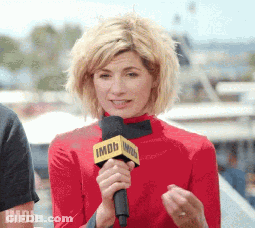 A Woman In A Red Top Is Holding A Microphone That Says Imdb On It GIF