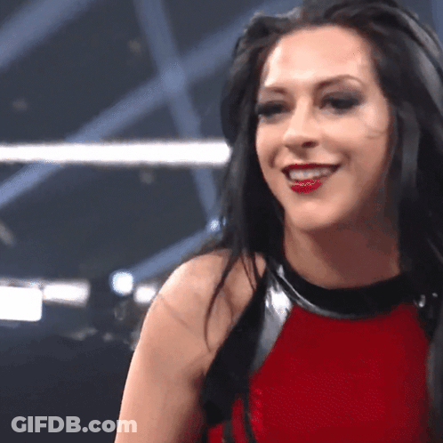 A Woman In A Red Top Is Smiling And Looking At The Camera GIF