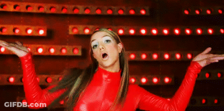 A Woman In A Red Top Is Standing In Front Of A Wall Of Red Lights . GIF