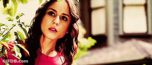 A Woman In A Red Top Is Standing In Front Of A Window . GIF