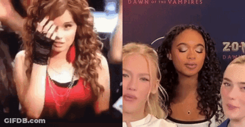 A Woman In A Red Top Is Standing Next To Another Woman In Front Of A Dawn Of The Vampires Poster GIF