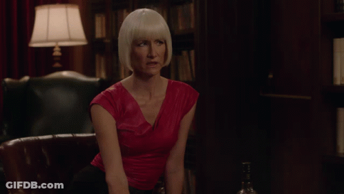 A Woman In A Red Top Sits On A Couch In Front Of A Lamp GIF