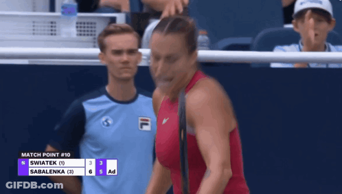 A Woman In A Red Top Stands In Front Of A Scoreboard That Says " Match Point # 10 " GIF