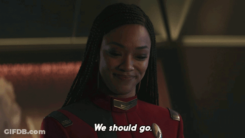 A Woman In A Red Uniform Says " We Should Go " In White Letters GIF