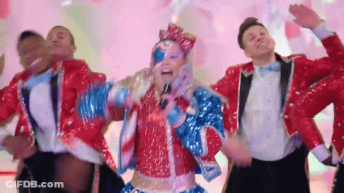 A Woman In A Red White And Blue Outfit Sings Into A Microphone GIF