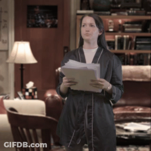 A Woman In A Robe Holds A Piece Of Paper In Her Hands GIF