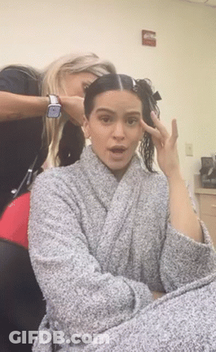 A Woman In A Robe Is Getting Her Hair Done By A Hairdresser GIF