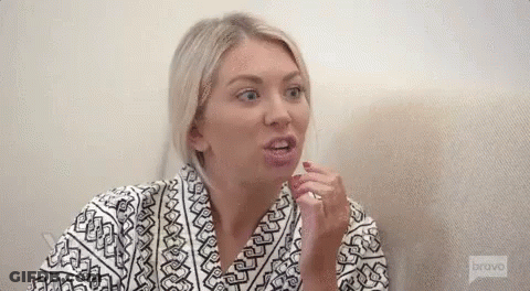 A Woman In A Robe Is Sitting On A Couch And Making A Funny Face . GIF
