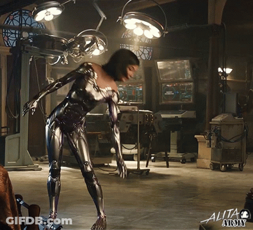 A Woman In A Robotic Suit Is In An Operating Room With The Word Alita Army On The Bottom Right GIF