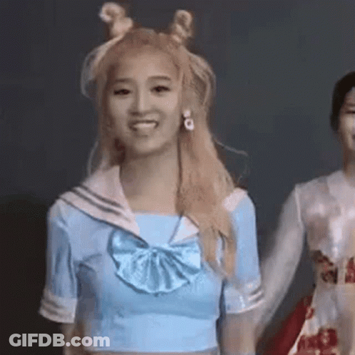 A Woman In A Sailor Suit Is Holding Hands With Another Woman In A White Dress . GIF