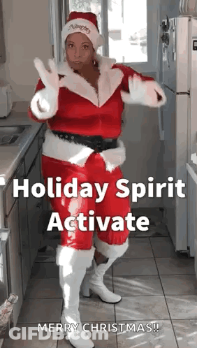 A Woman In A Santa Costume Is Dancing In A Kitchen . GIF