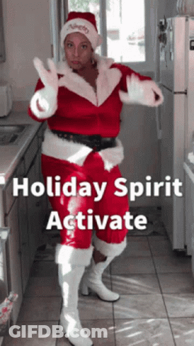 A Woman In A Santa Costume Is Dancing In A Kitchen GIF