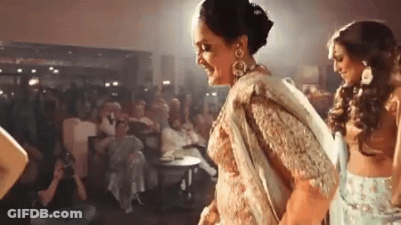 A Woman In A Sari Is Dancing In Front Of A Crowd Of People . GIF