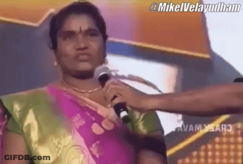A Woman In A Sari Is Holding A Microphone In Front Of Her Face .. GIF