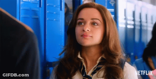 A Woman In A School Uniform And Tie Is Standing In Front Of Blue Lockers With A Netflix Logo In The Corner . GIF