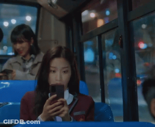 A Woman In A School Uniform Is Looking At Her Cell Phone GIF