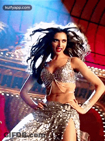 A Woman In A Sequined Dress Is Dancing In Front Of A Crowd . GIF