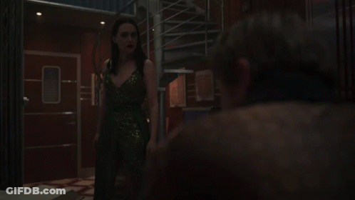 A Woman In A Sequined Dress Stands Next To A Man GIF