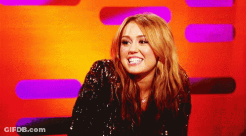 A Woman In A Sequined Jacket Smiles In Front Of A Purple And Orange Background GIF