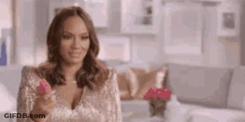 A Woman In A Sequined Top Is Holding A Pink Object In Her Hand . GIF