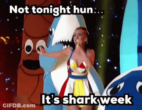 A Woman In A Shark Costume Is Singing Into A Microphone .. GIF