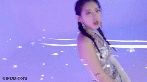 A Woman In A Silver Dress Is Standing In A Purple Room . GIF