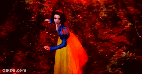 A Woman In A Snow White Costume Is Standing In A Red Forest . GIF