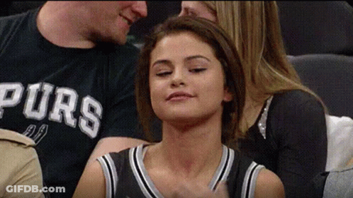 A Woman In A Spurs Shirt Is Sitting In The Stands With Her Eyes Closed . GIF