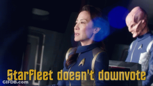 A Woman In A Star Fleet Uniform Stands Next To A Man In A Star Trek Uniform GIF