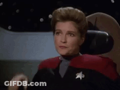 A Woman In A Star Trek Uniform Is Sitting In A Chair And Making A Face . GIF