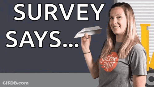 A Woman In A Sticker Giant Shirt Holds A Paper Airplane In Front Of A Sign That Says Survey Says GIF