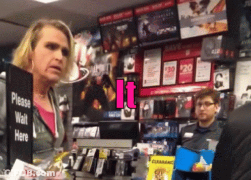 A Woman In A Store Behind A Sign That Says Please Wait Here GIF