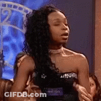 A Woman In A Strapless Black Dress Is Sitting On A Couch With Her Eyes Closed . GIF