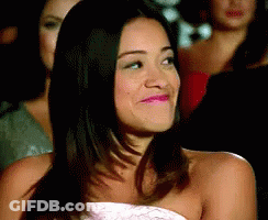 A Woman In A Strapless Dress Is Smiling In Front Of A Group Of Women . GIF