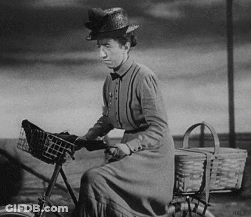 A Woman In A Straw Hat Is Riding A Bicycle GIF