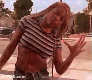 A Woman In A Striped Crop Top And Shorts Is Dancing On The Street . GIF